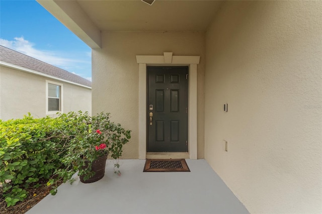 doorway to property featuring stucco siding