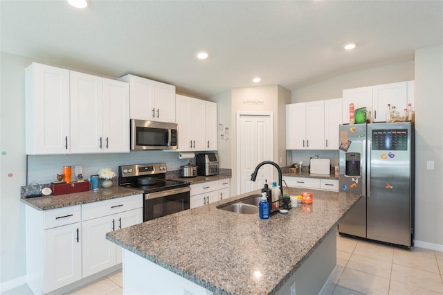 kitchen featuring a kitchen island with sink, stainless steel appliances, sink, white cabinetry, and lofted ceiling