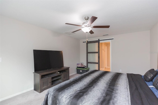 bedroom with a barn door, ceiling fan, and light colored carpet