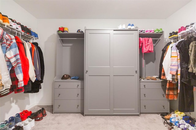 walk in closet with light carpet