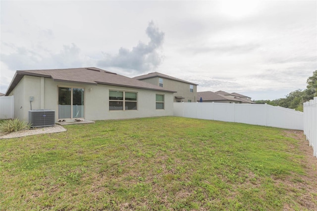 rear view of house featuring a lawn and central air condition unit