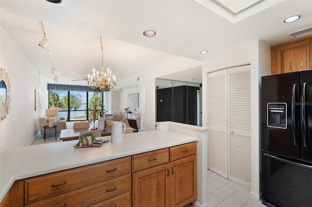 kitchen with black fridge, pendant lighting, and a chandelier