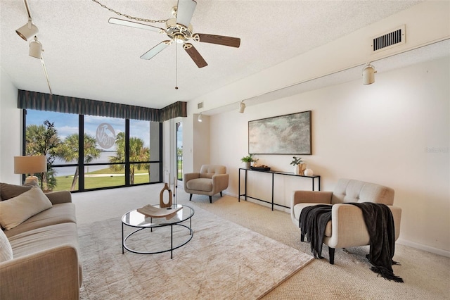 carpeted living room with ceiling fan and a textured ceiling