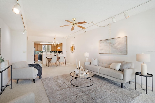 carpeted living room with rail lighting and ceiling fan with notable chandelier