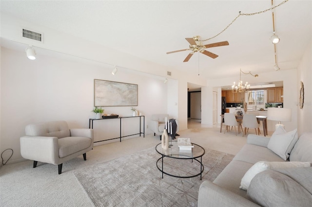 carpeted living room featuring ceiling fan with notable chandelier