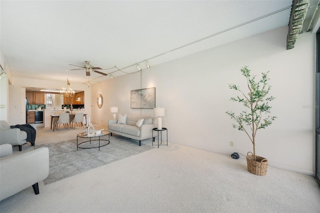 carpeted living room with rail lighting and ceiling fan with notable chandelier