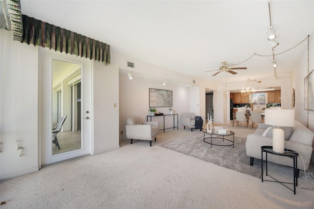 carpeted living room with ceiling fan with notable chandelier