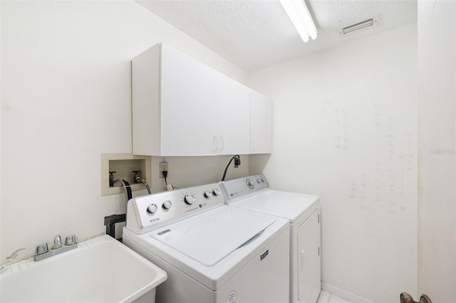 clothes washing area featuring washer and dryer, cabinets, sink, and a textured ceiling