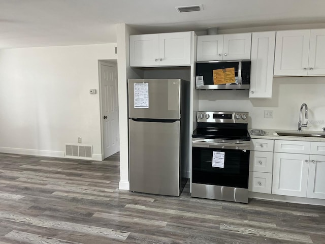 kitchen with dark wood-type flooring, white cabinetry, stainless steel appliances, and sink