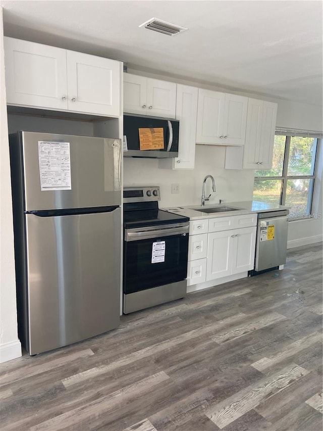 kitchen with dark wood-type flooring, white cabinetry, stainless steel appliances, and sink