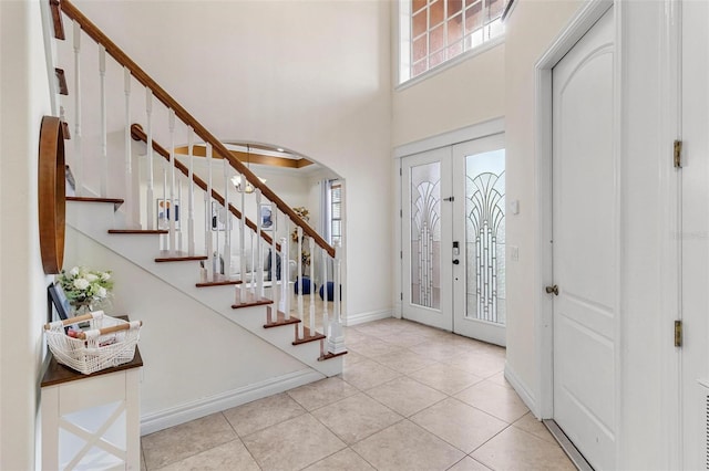 foyer entrance featuring french doors, a towering ceiling, and light tile patterned floors