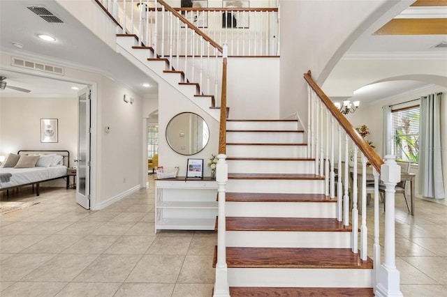 stairs featuring ornamental molding, ceiling fan with notable chandelier, and tile patterned floors