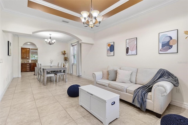 tiled living room featuring a notable chandelier, a tray ceiling, and ornamental molding