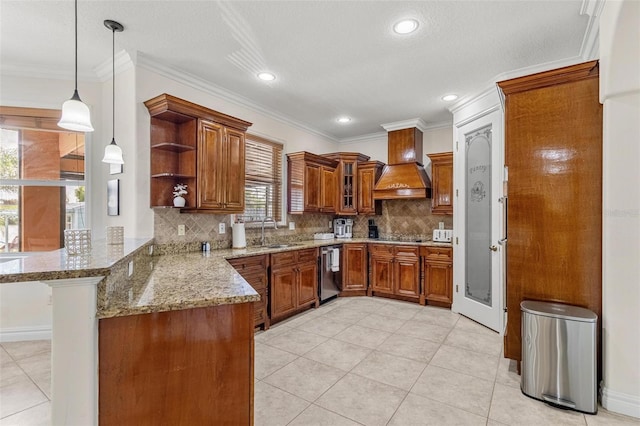 kitchen featuring sink, kitchen peninsula, hanging light fixtures, custom exhaust hood, and light stone countertops