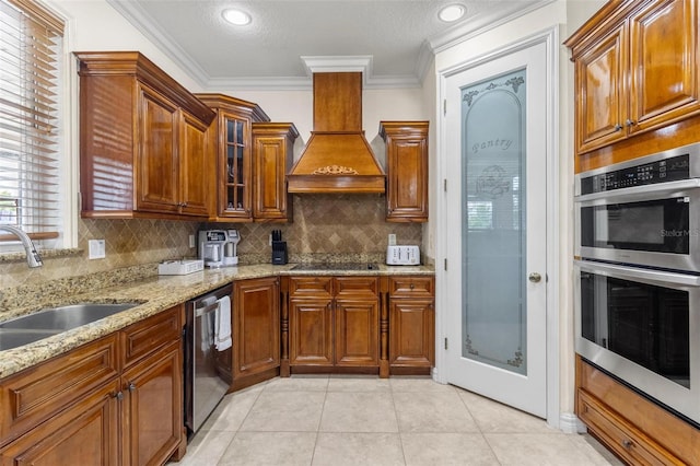 kitchen with light stone counters, light tile patterned floors, stainless steel appliances, premium range hood, and ornamental molding