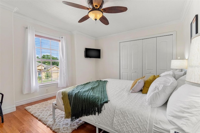 bedroom with crown molding, ceiling fan, a closet, and hardwood / wood-style flooring