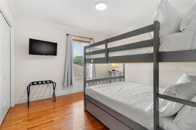 bedroom with ornamental molding, a closet, and hardwood / wood-style floors