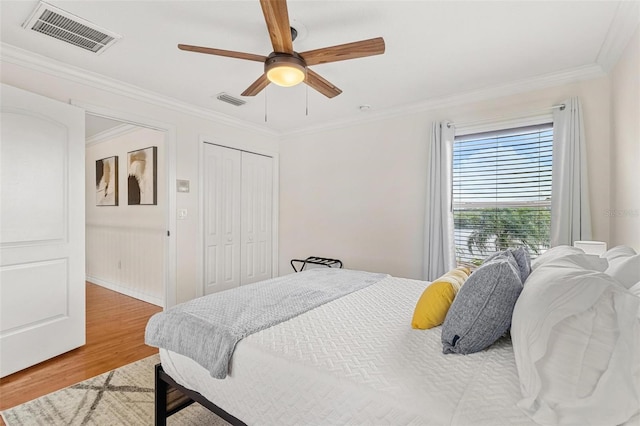 bedroom with ceiling fan, a closet, crown molding, and hardwood / wood-style floors