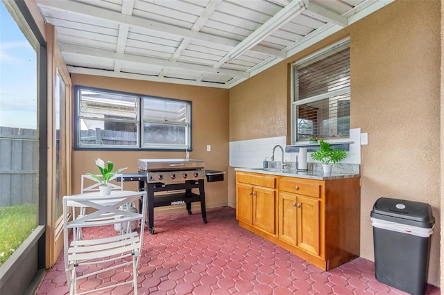 sunroom with beamed ceiling, sink, and a wealth of natural light