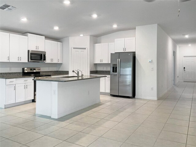 kitchen with a center island with sink, stainless steel appliances, white cabinetry, lofted ceiling, and light tile patterned flooring