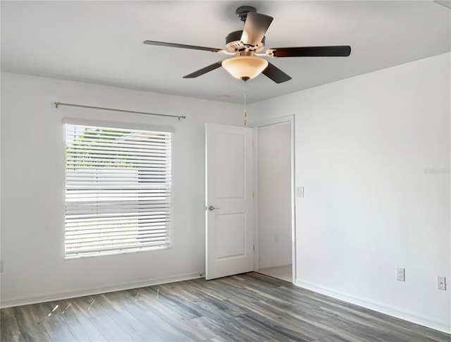 unfurnished room with baseboards, wood finished floors, and a ceiling fan