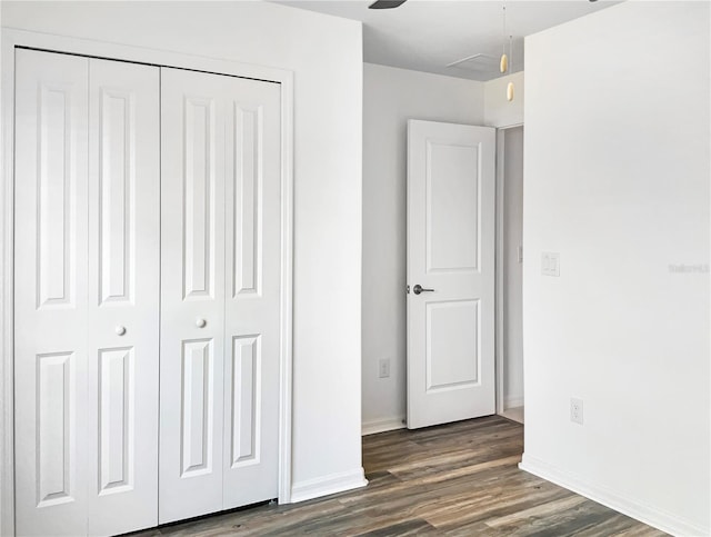 unfurnished bedroom with a closet, baseboards, and dark wood-style flooring