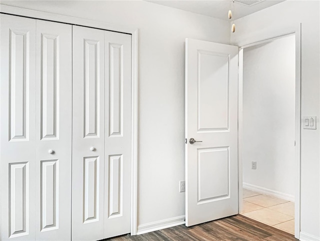 unfurnished bedroom featuring wood finished floors, a closet, and baseboards