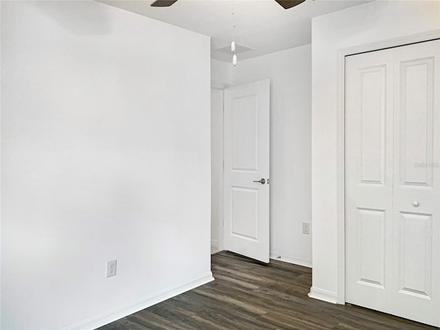 unfurnished bedroom with a closet, baseboards, a ceiling fan, and dark wood-style flooring