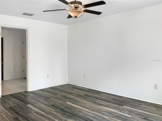 spare room with visible vents, baseboards, dark wood-type flooring, and ceiling fan