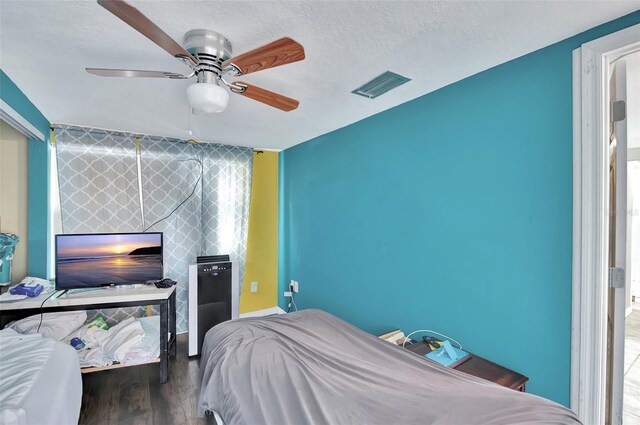 bedroom featuring a textured ceiling, ceiling fan, and dark hardwood / wood-style flooring