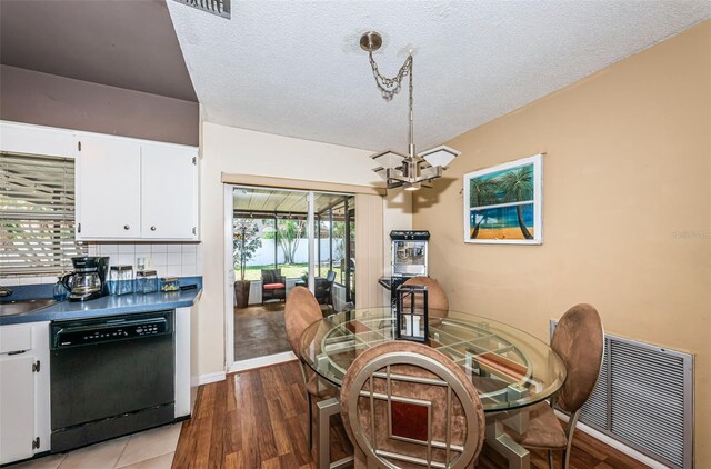 dining space with a textured ceiling, light hardwood / wood-style flooring, and a chandelier