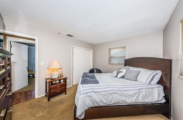 bedroom featuring a textured ceiling, light colored carpet, and a closet