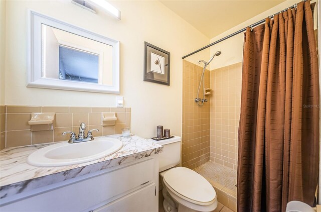 bathroom featuring walk in shower, toilet, backsplash, and vanity