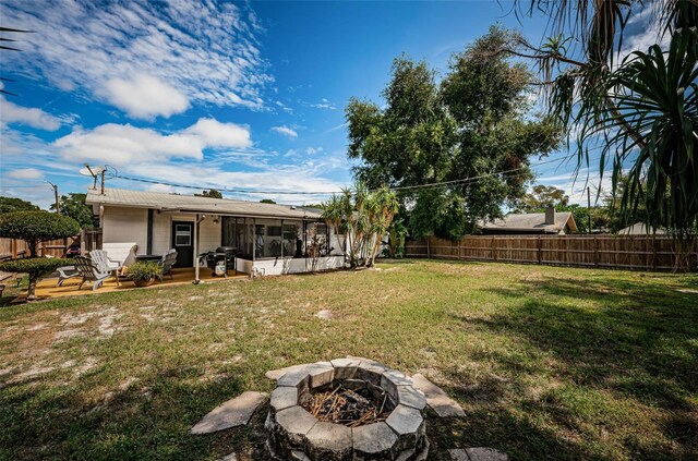 view of yard featuring a fire pit and a sunroom