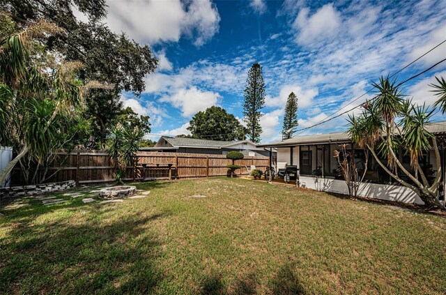 view of yard featuring an outdoor fire pit and a sunroom