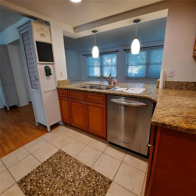 kitchen featuring stainless steel dishwasher, sink, light tile patterned flooring, and decorative light fixtures