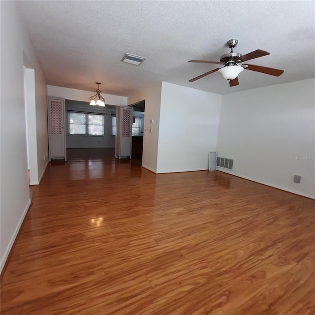 unfurnished room with a textured ceiling, ceiling fan with notable chandelier, and dark hardwood / wood-style flooring