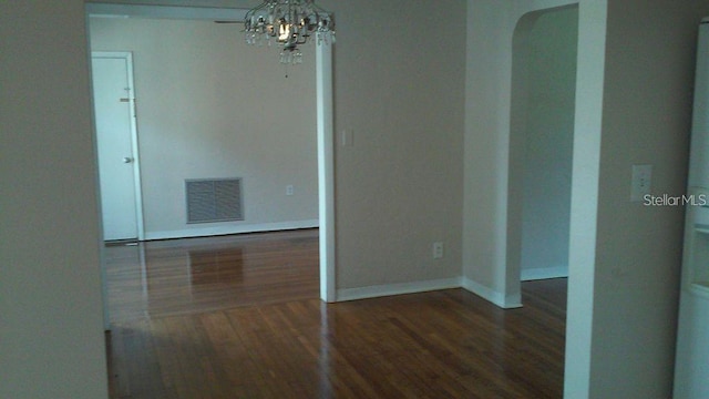 unfurnished room featuring a notable chandelier and dark hardwood / wood-style floors