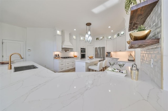 kitchen featuring white cabinets, a center island, premium range hood, and sink