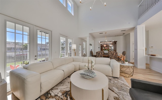 living room with a towering ceiling, a wealth of natural light, and a chandelier