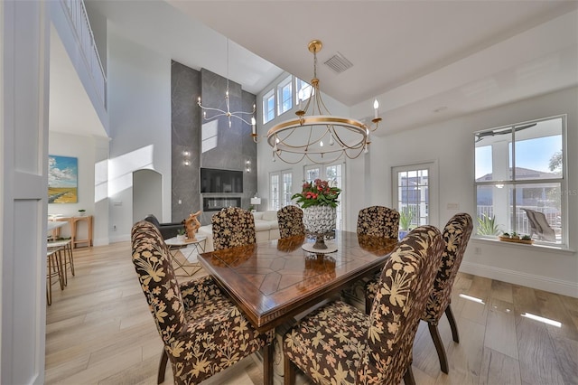 dining space with light hardwood / wood-style flooring, a high end fireplace, and a chandelier