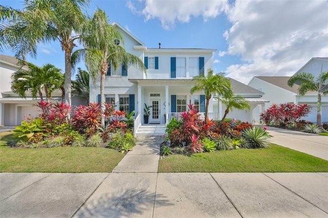 view of front of property with covered porch, driveway, a garage, and stucco siding