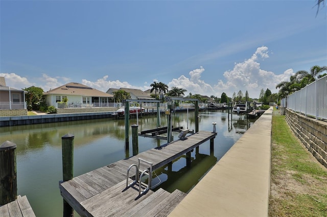 view of dock featuring a water view, boat lift, a residential view, and fence