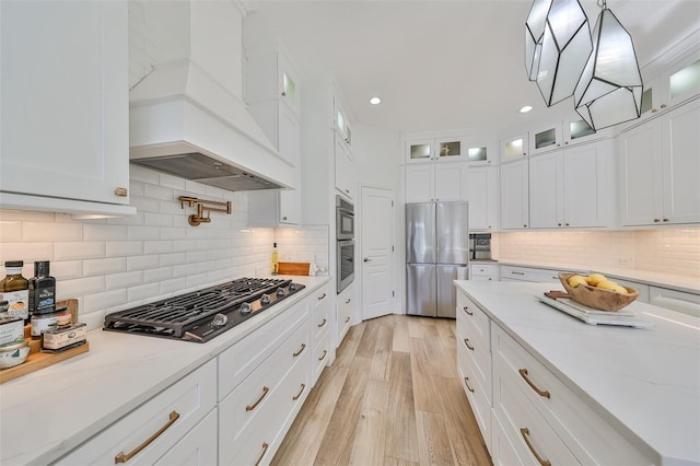 kitchen featuring freestanding refrigerator, custom exhaust hood, light wood-style floors, gas stovetop, and white cabinetry