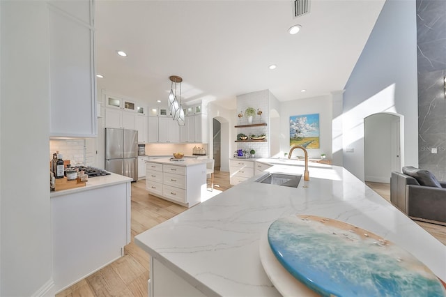 kitchen with visible vents, decorative backsplash, arched walkways, appliances with stainless steel finishes, and a sink