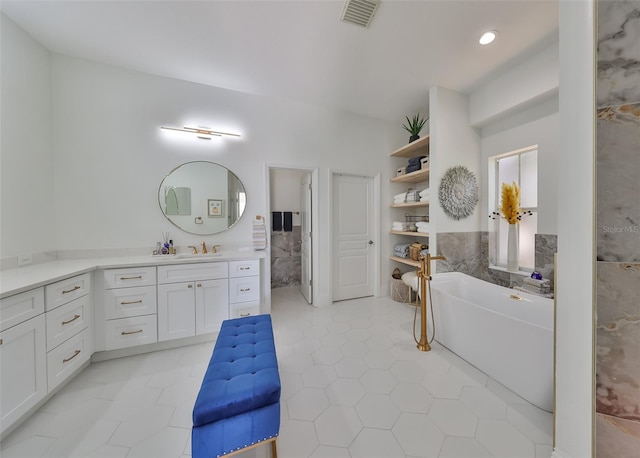 bathroom with tile walls, visible vents, vanity, tile patterned flooring, and a freestanding tub