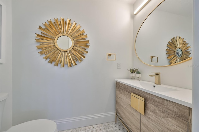 bathroom with toilet, tile patterned floors, baseboards, and vanity