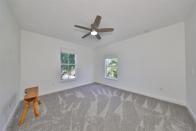 carpeted spare room featuring ceiling fan and baseboards