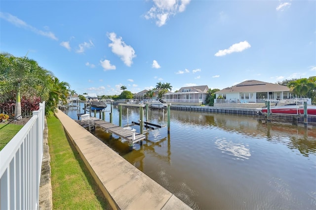 view of dock featuring a water view, boat lift, and a residential view