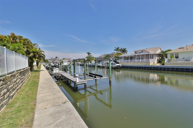 view of dock featuring a water view, boat lift, a residential view, and fence